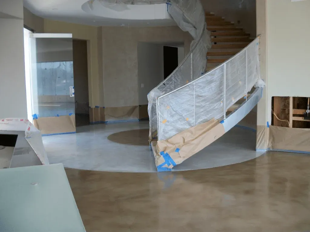 Stained interior concrete floor with circular design under a curved staircase, residential concrete staining near Kennesaw GA