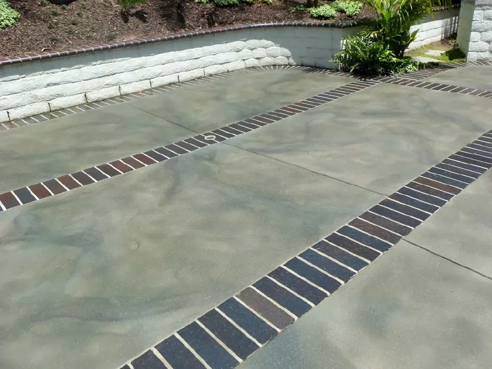 Stained concrete driveway court with brick banding by JP Concrete Creations