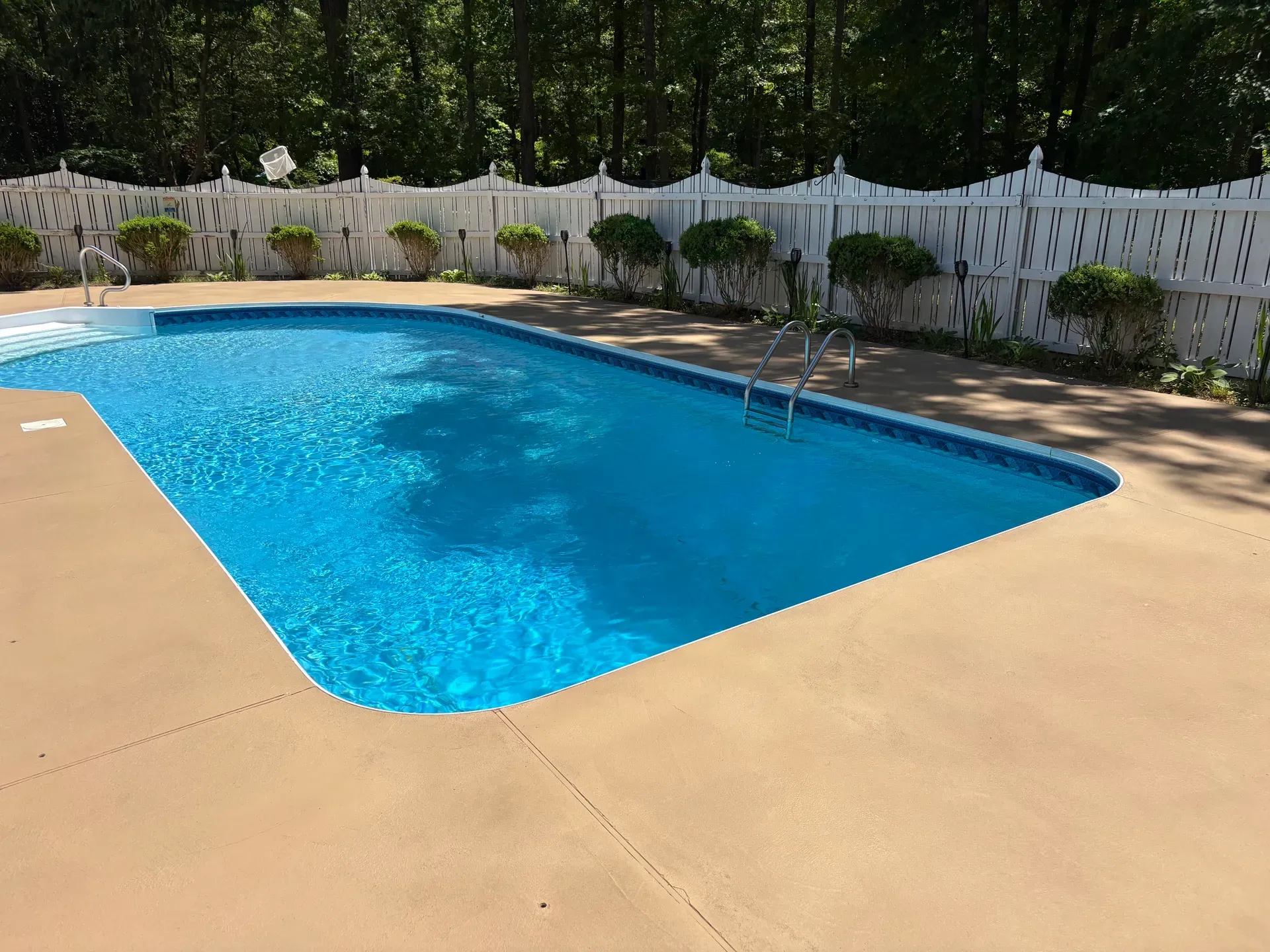 Resurfaced tan concrete pool deck around an in-ground pool in North Georgia