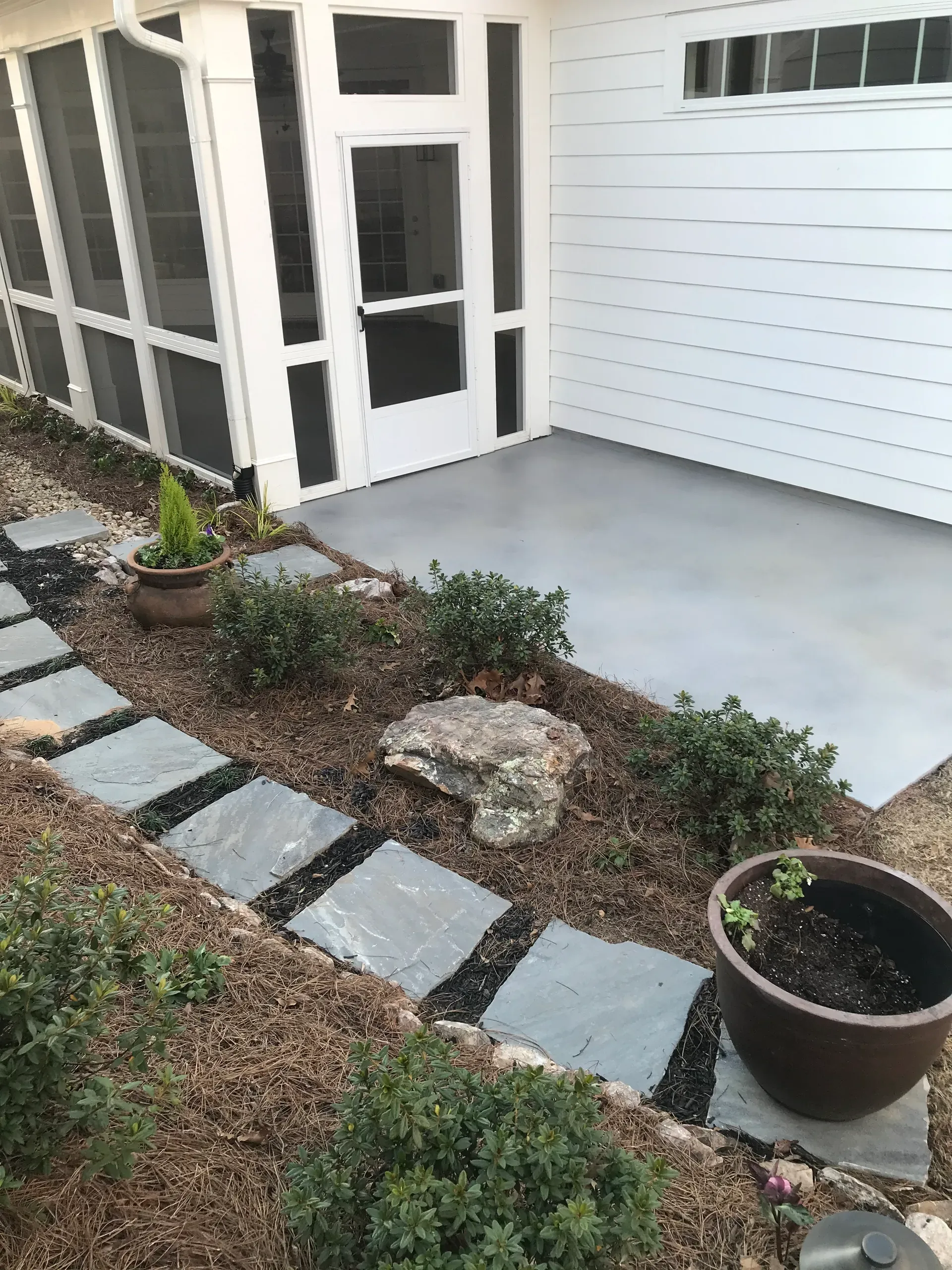 Gray stained concrete patio beside a screened porch with slate walkway in Georgia
