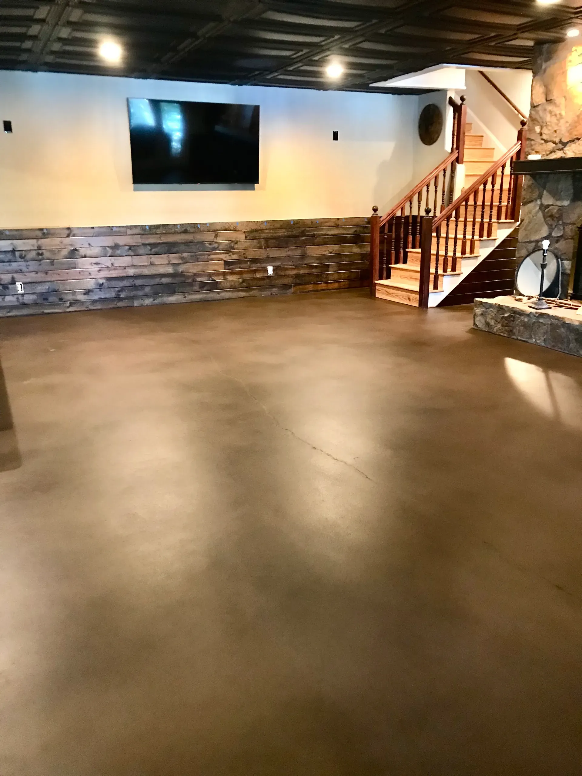 Warm brown stained basement concrete floor in a finished Georgia basement with stone fireplace